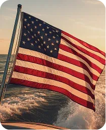 An American flag flying from a boat over the water